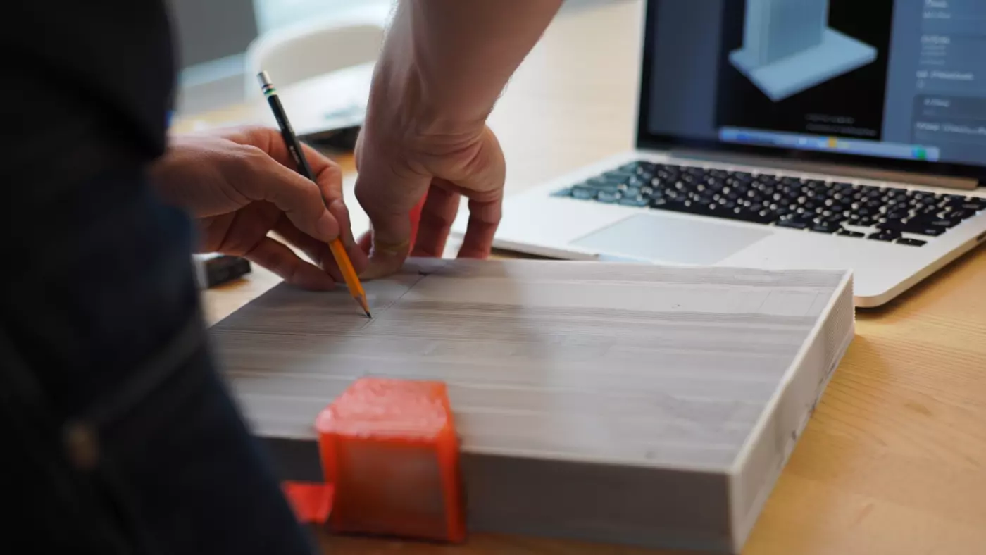 Tekniker gennemgår 3D model på laptop med printet prøveemne på bordet